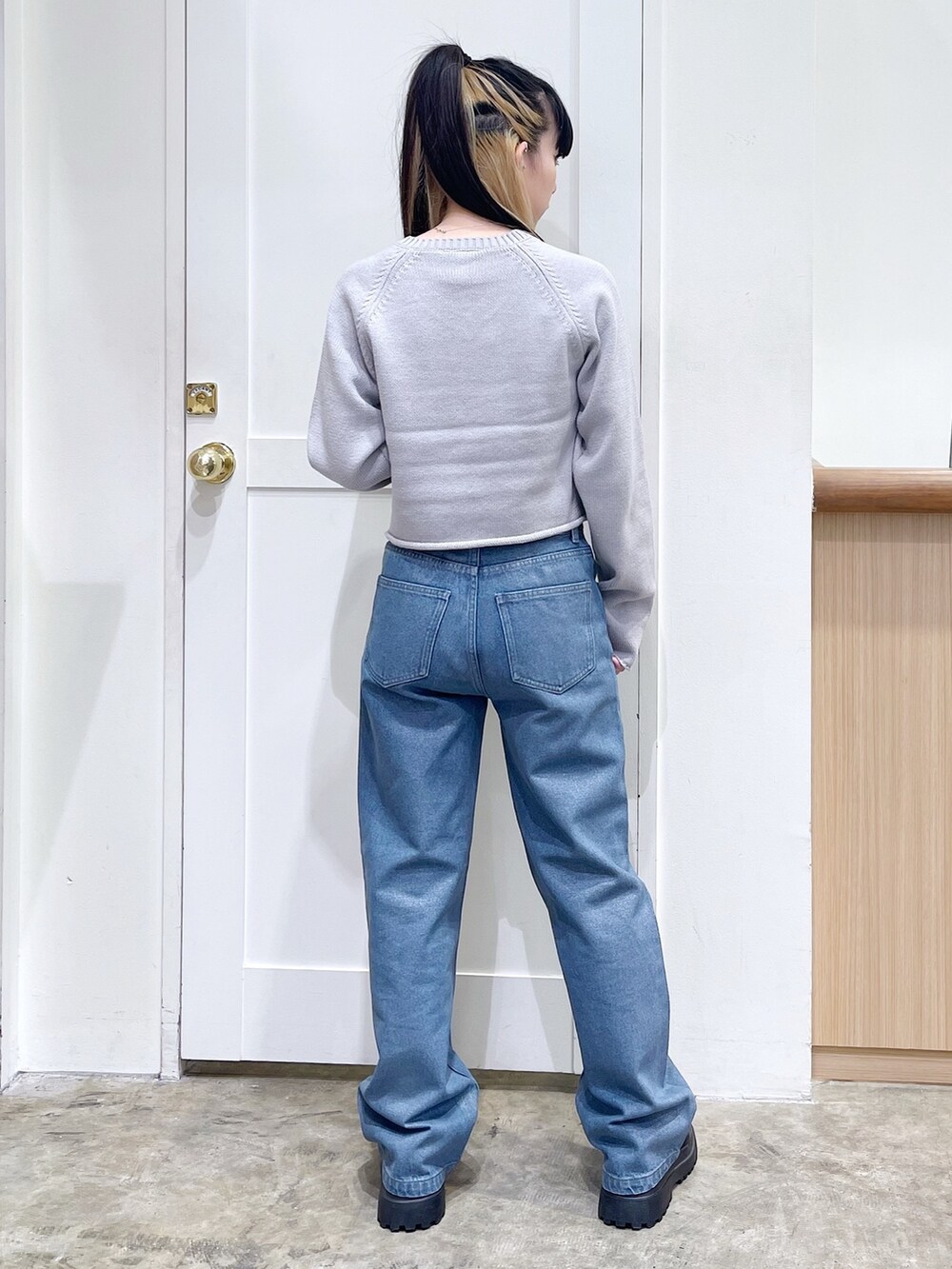 グレー系のニット/セーター、ブルー系のデニムパンツ、ベージュ系のハンドバッグを着用したレディースの秋コーディネートの4枚目の写真