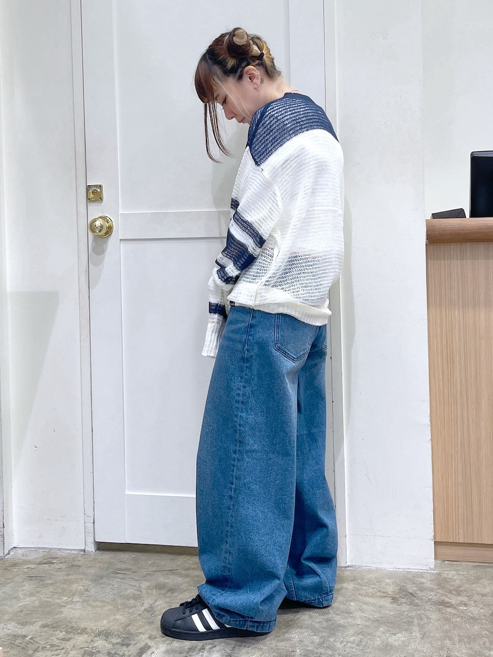 ホワイト系のニット/セーター、ホワイト系のTシャツ/カットソー、ブルー系のデニムパンツを着用したレディースの秋コーディネートの2枚目の写真