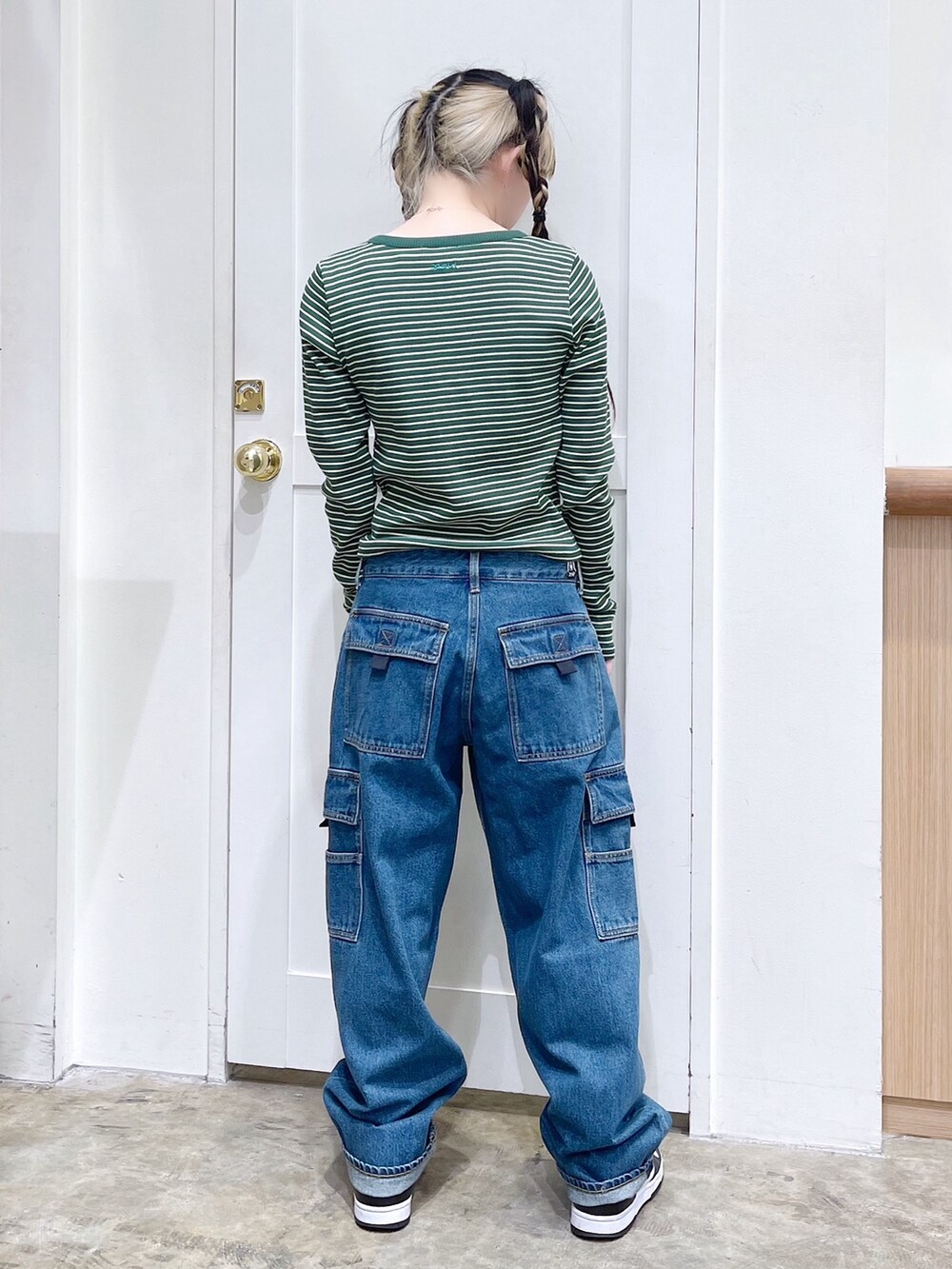 グリーン系のTシャツ/カットソー、ブルー系のデニムパンツ、ブラック系のショルダーバッグを着用したレディースの冬コーディネートの3枚目の写真