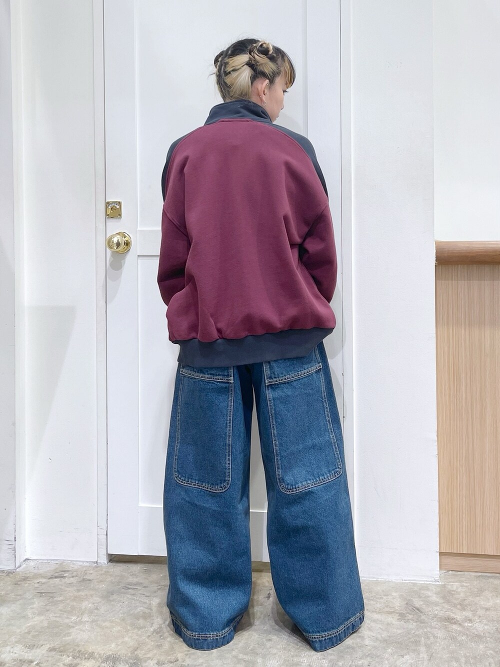 レッド系のスウェット、ブルー系のボストンバッグ、ブルー系のデニムパンツを着用したレディースの冬コーディネートの4枚目の写真