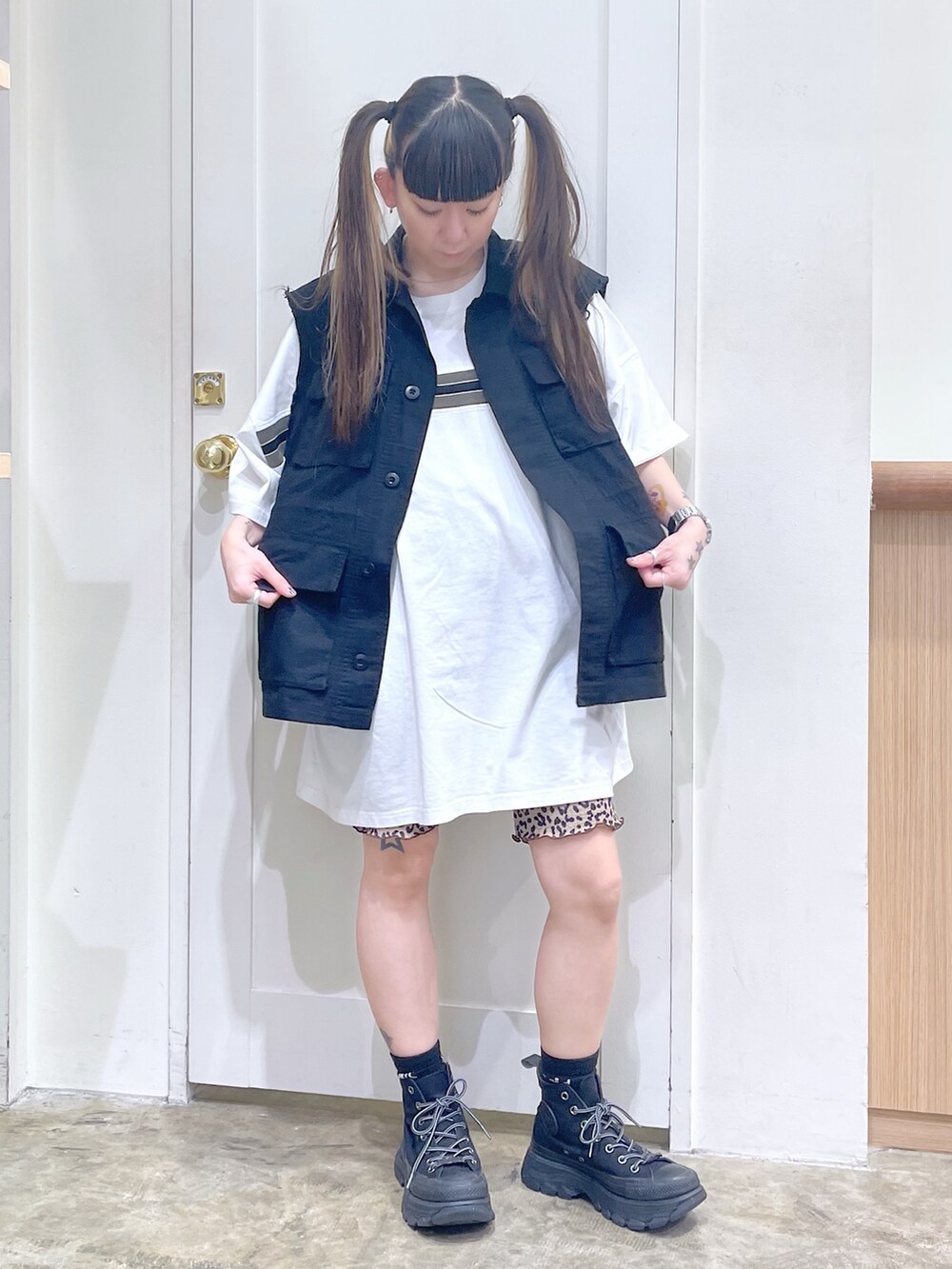 ブラック系のベスト、ホワイト系のワンピース、ブラック系のスニーカーを着用したレディースの夏コーディネートの2枚目の写真