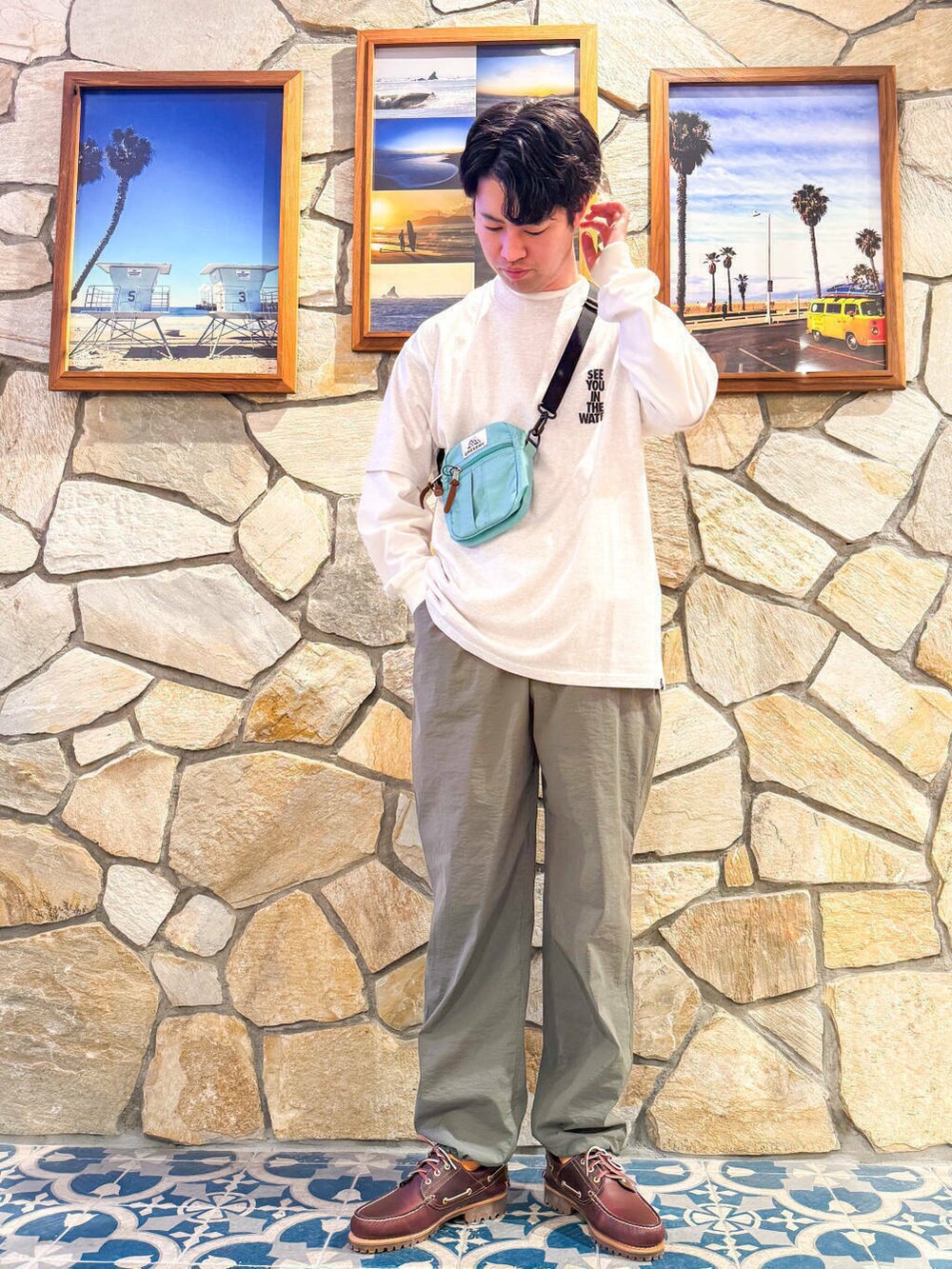 レッド系のモカシン/デッキシューズ、グレー系のTシャツ/カットソー、グリーン系のショルダーバッグを着用したメンズの春コーディネートの3枚目の写真