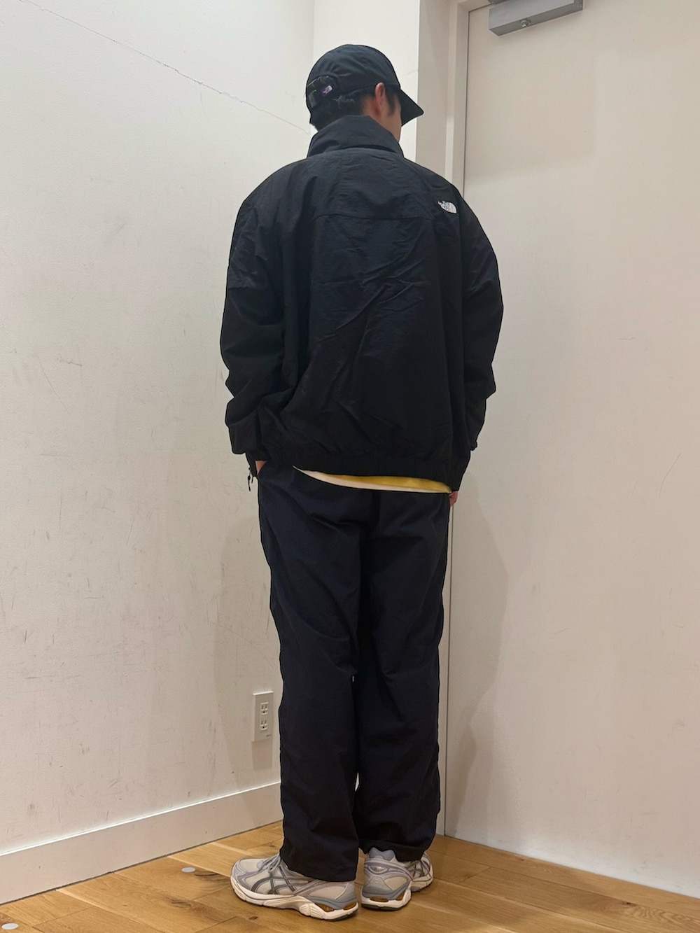 ブラック系のブルゾン、イエロー系のTシャツ/カットソー、ホワイト系のスニーカーを着用したメンズの冬コーディネートの2枚目の写真