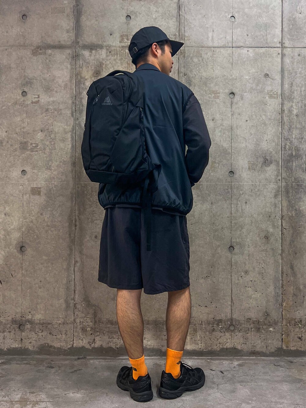 グレー系のTシャツ/カットソー、ブラック系のベスト、ブラック系のバックパック/リュックを着用したメンズの秋コーディネートの2枚目の写真