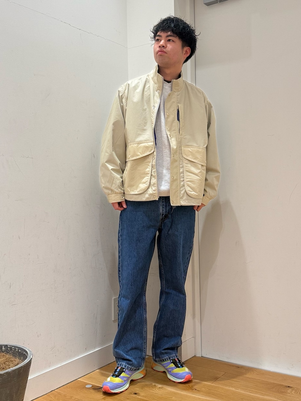 グレー系のスウェット、ブルー系のデニムパンツ、ホワイト系のテーラードジャケットを着用したメンズの冬コーディネートの2枚目の写真