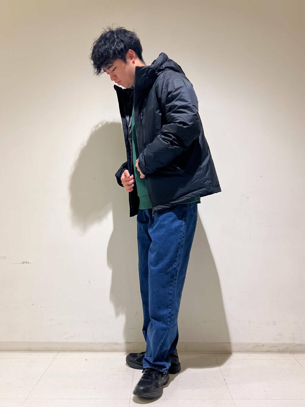 ブルー系のデニムパンツ、ブラック系のダウンジャケット/コート、グリーン系のスウェットを着用したメンズの秋コーディネートの3枚目の写真
