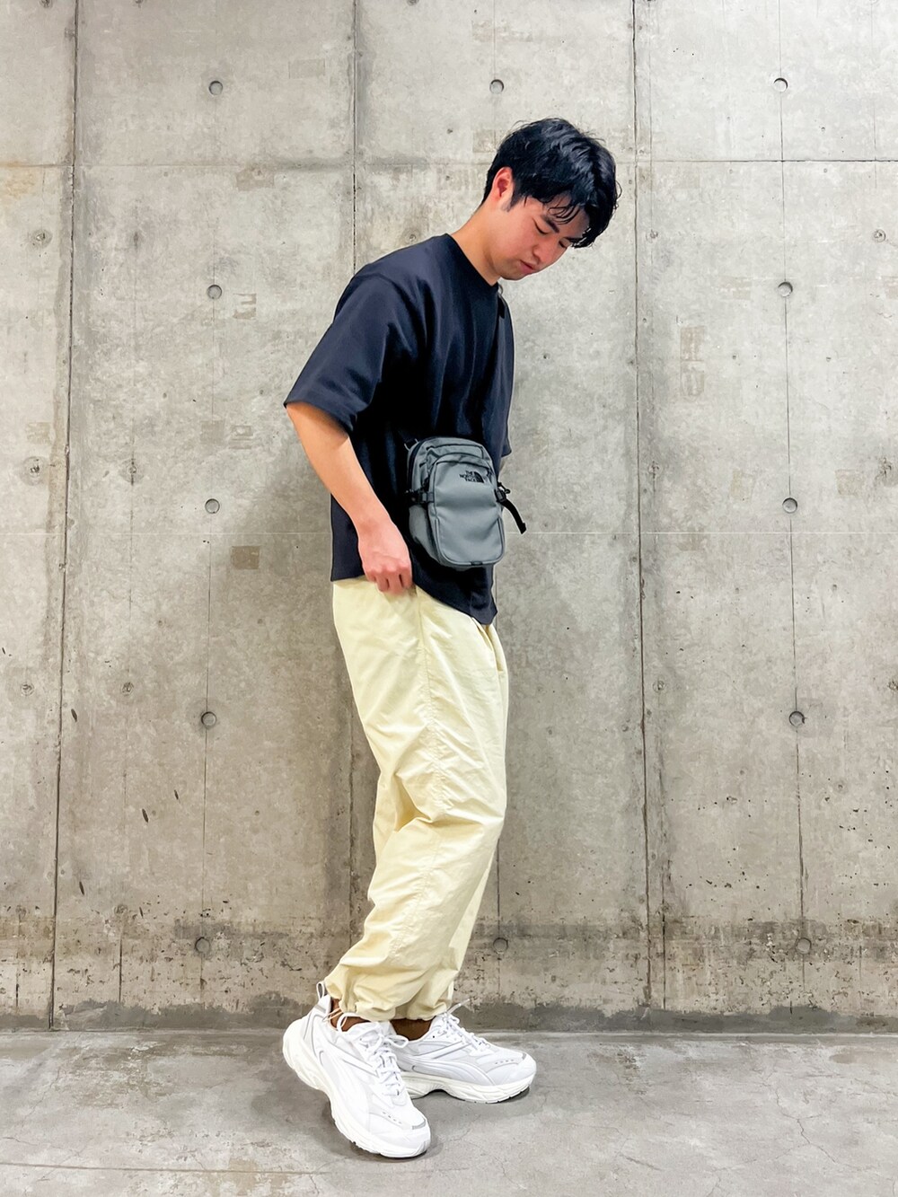 ブラック系のトップス、グレー系のショルダーバッグ、ベージュ系のその他パンツを着用したメンズの春コーディネートの2枚目の写真