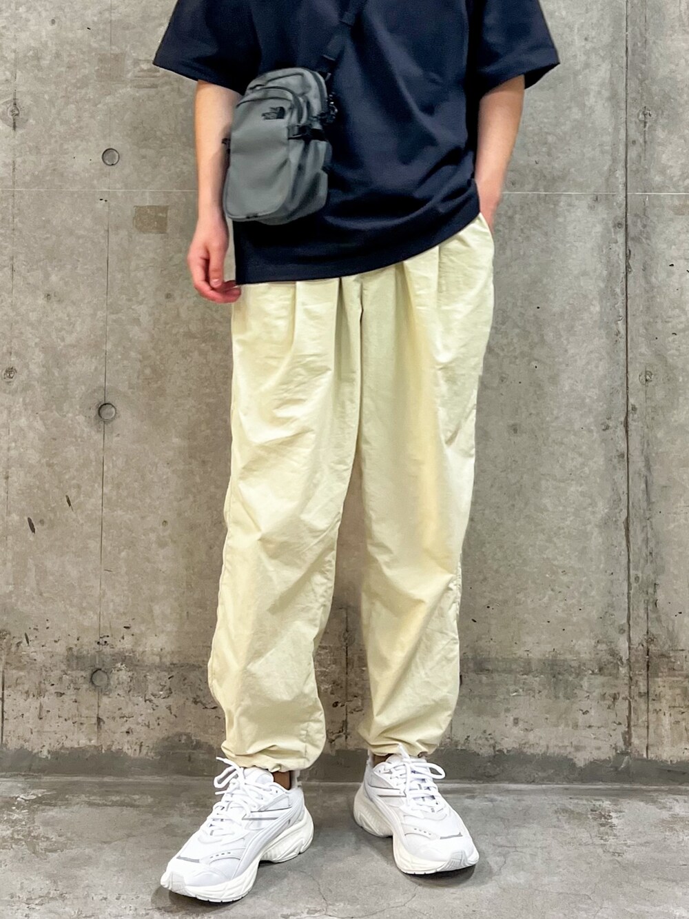 ブラック系のトップス、グレー系のショルダーバッグ、ベージュ系のその他パンツを着用したメンズの春コーディネートの3枚目の写真