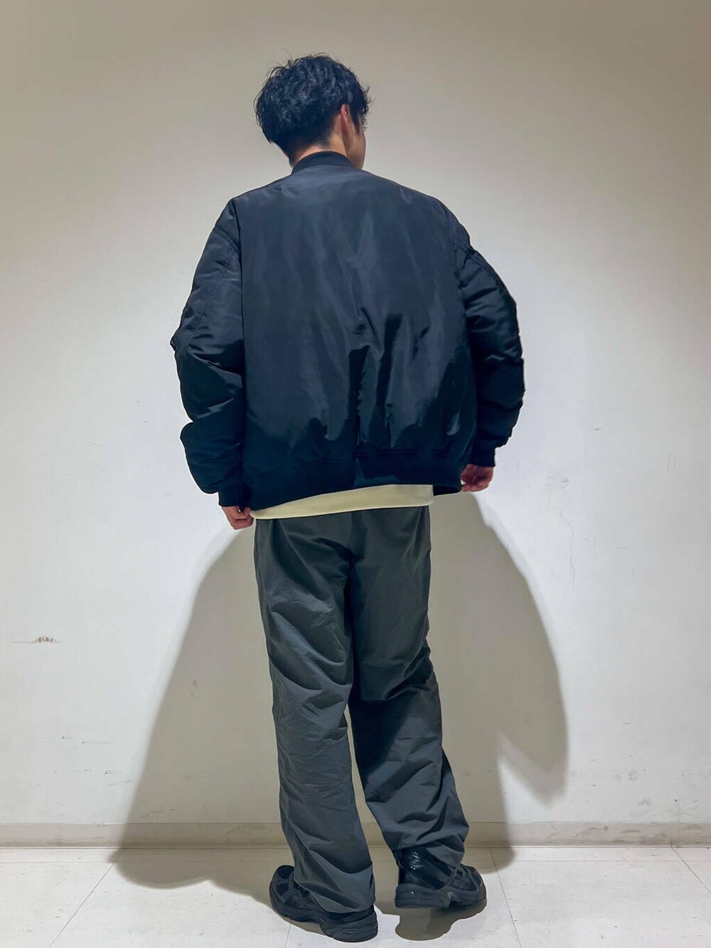 グレー系のその他パンツ、ホワイト系のTシャツ/カットソー、ブラック系のMA-1を着用したメンズの秋コーディネートの3枚目の写真