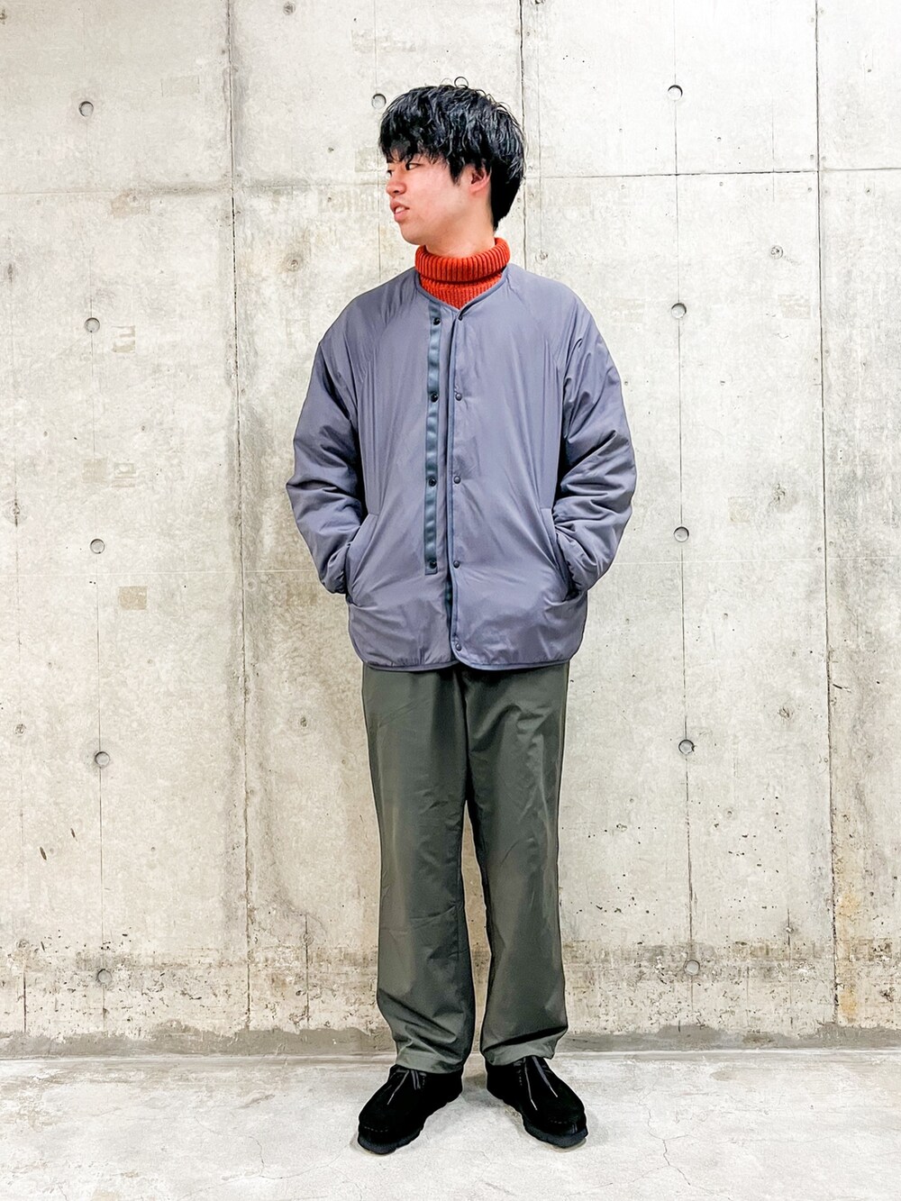 オレンジ系のニット/セーター、ブラック系のその他パンツ、グレー系のナイロンジャケットを着用したメンズの冬コーディネートの2枚目の写真