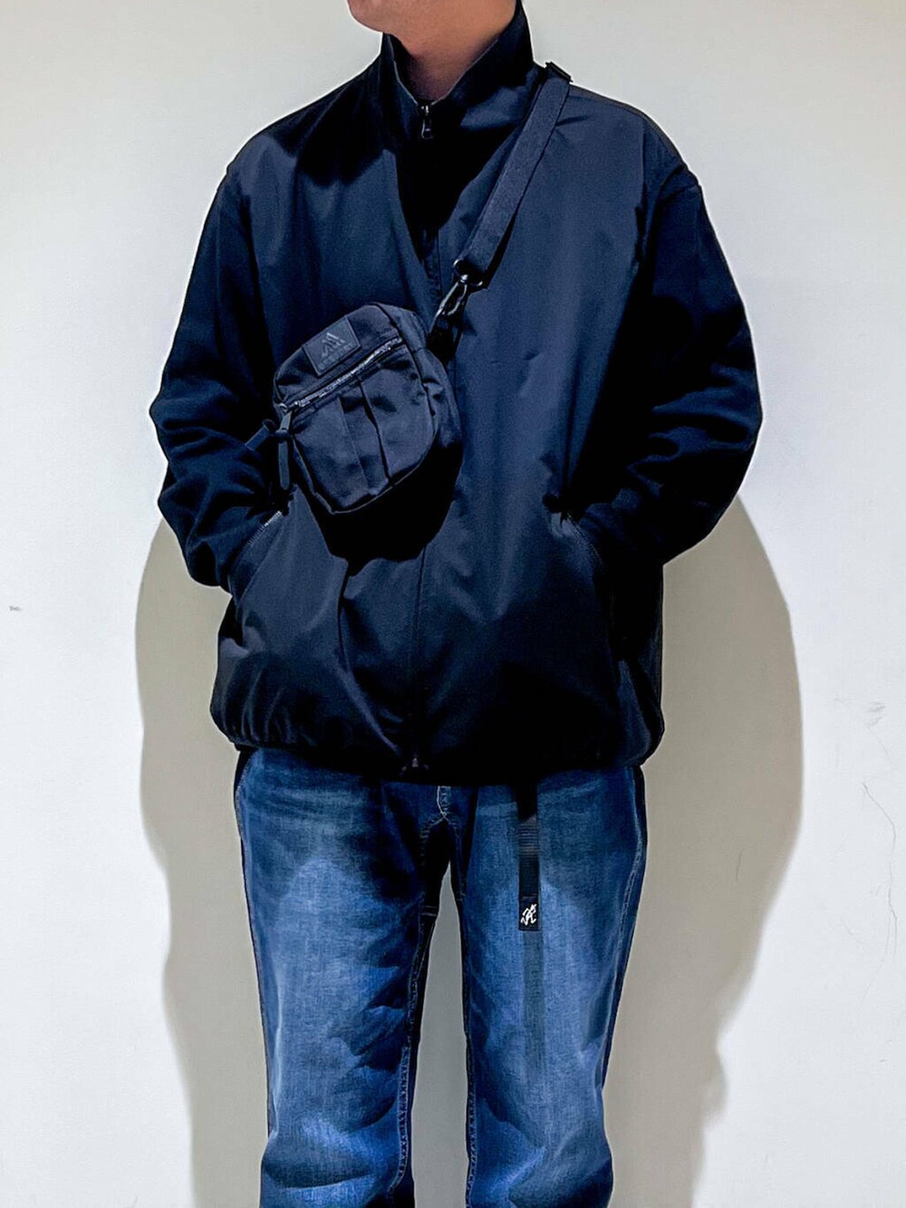 ブルー系のデニムパンツ、ブラック系のTシャツ/カットソー、ブラック系のベストを着用したメンズの秋コーディネートの3枚目の写真