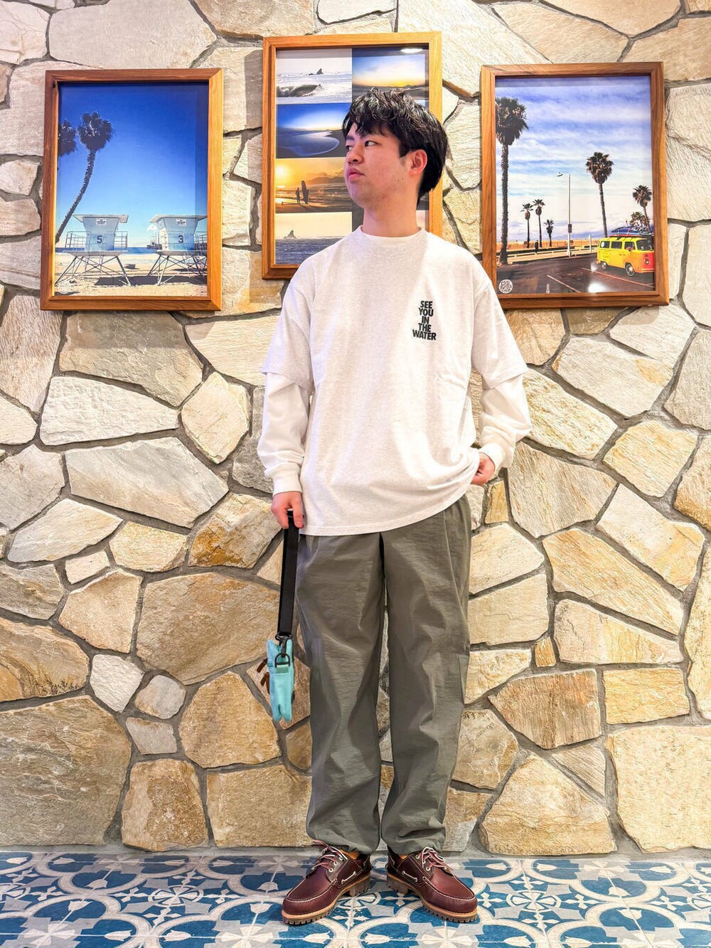 レッド系のモカシン/デッキシューズ、グレー系のTシャツ/カットソー、グリーン系のショルダーバッグを着用したメンズの春コーディネートの2枚目の写真