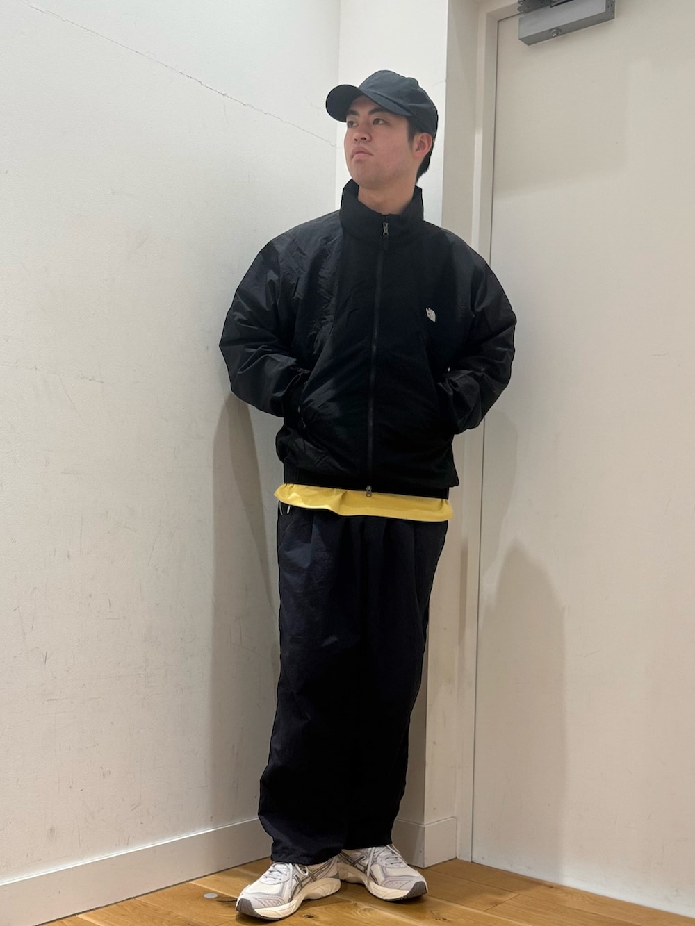 ブラック系のブルゾン、イエロー系のTシャツ/カットソー、ホワイト系のスニーカーを着用したメンズの冬コーディネートの3枚目の写真