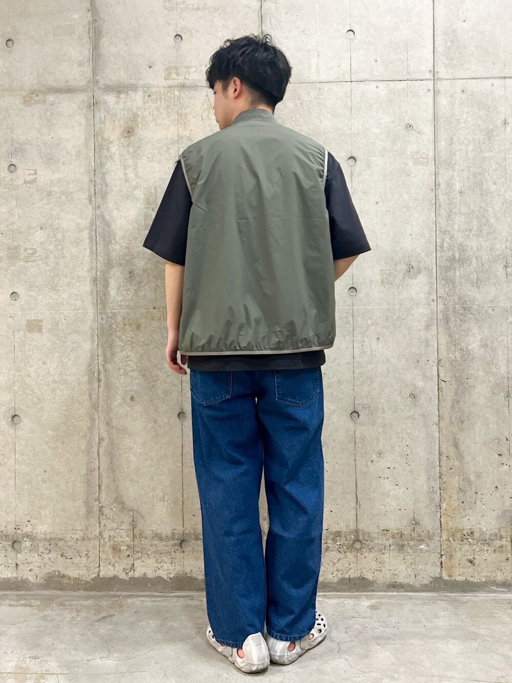 グリーン系のベスト、グレー系のTシャツ/カットソー、ブルー系のデニムパンツを着用したメンズの春コーディネートの2枚目の写真