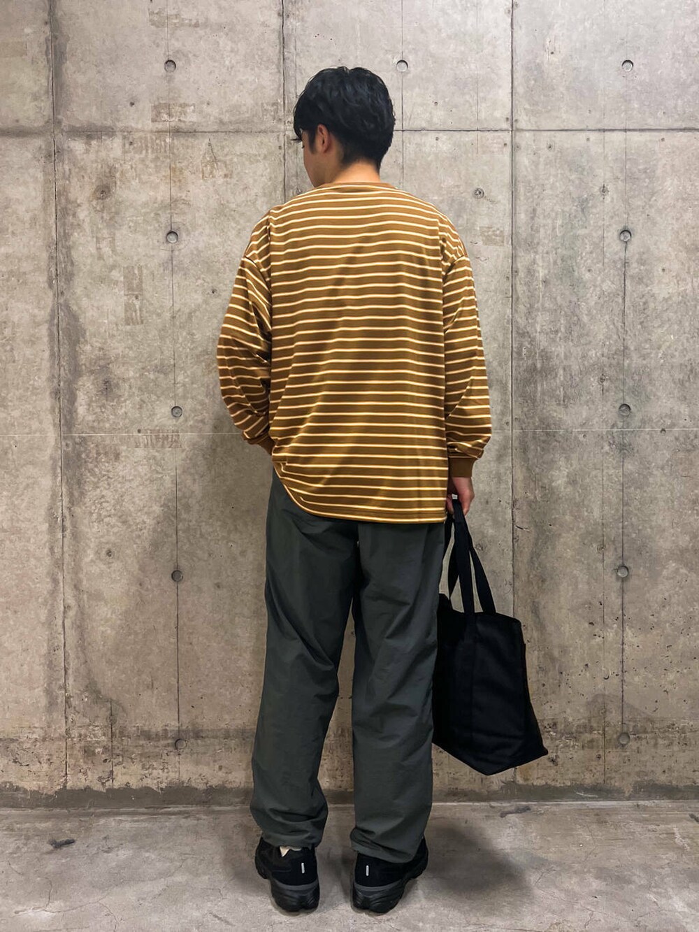 グレー系のその他パンツ、ブラック系のトートバッグ、ベージュ系のTシャツ/カットソーを着用したメンズの秋コーディネートの3枚目の写真