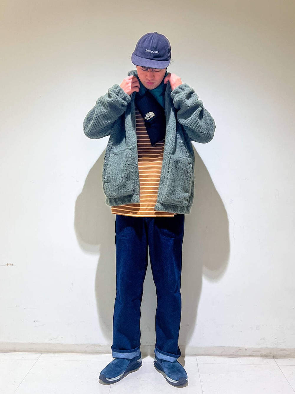 ブルー系のデニムパンツ、ベージュ系のTシャツ/カットソー、グリーン系のブルゾンを着用したメンズの秋コーディネートの2枚目の写真