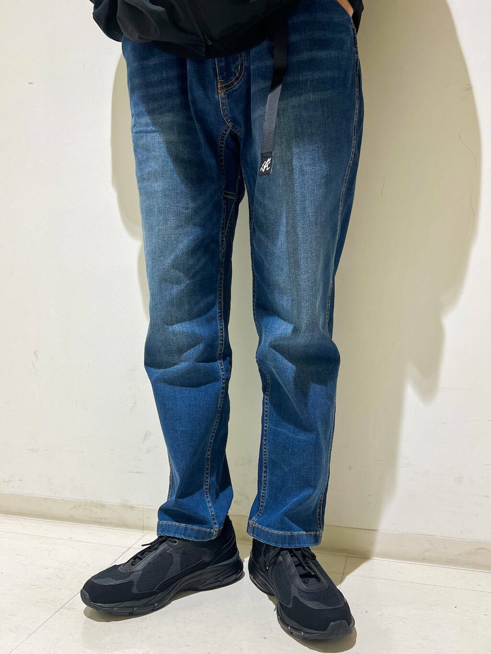 ブルー系のデニムパンツ、ブラック系のTシャツ/カットソー、ブラック系のベストを着用したメンズの秋コーディネートの4枚目の写真