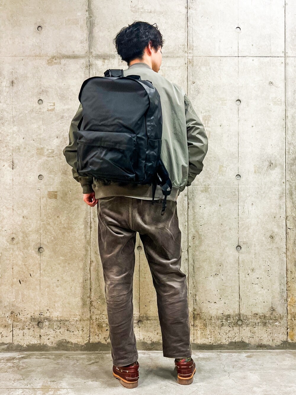 グリーン系のナイロンジャケット、グレー系のその他パンツ、ブラック系のバックパック/リュックを着用したメンズの冬コーディネートの2枚目の写真