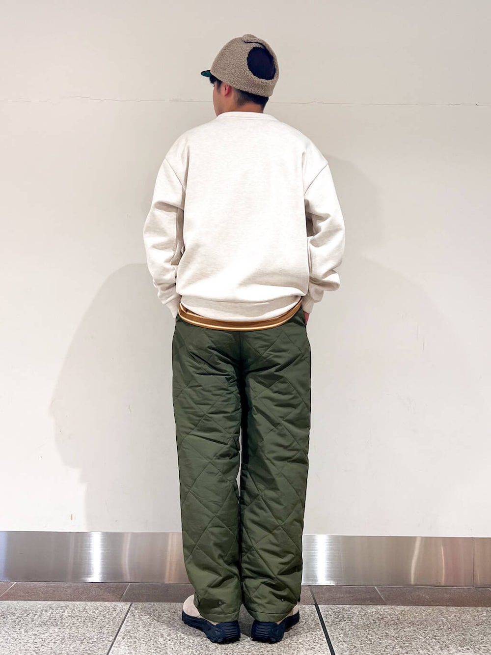 グリーン系のその他パンツ、ベージュ系のスウェット、ブラウン系のキャップを着用したメンズの冬コーディネートの2枚目の写真