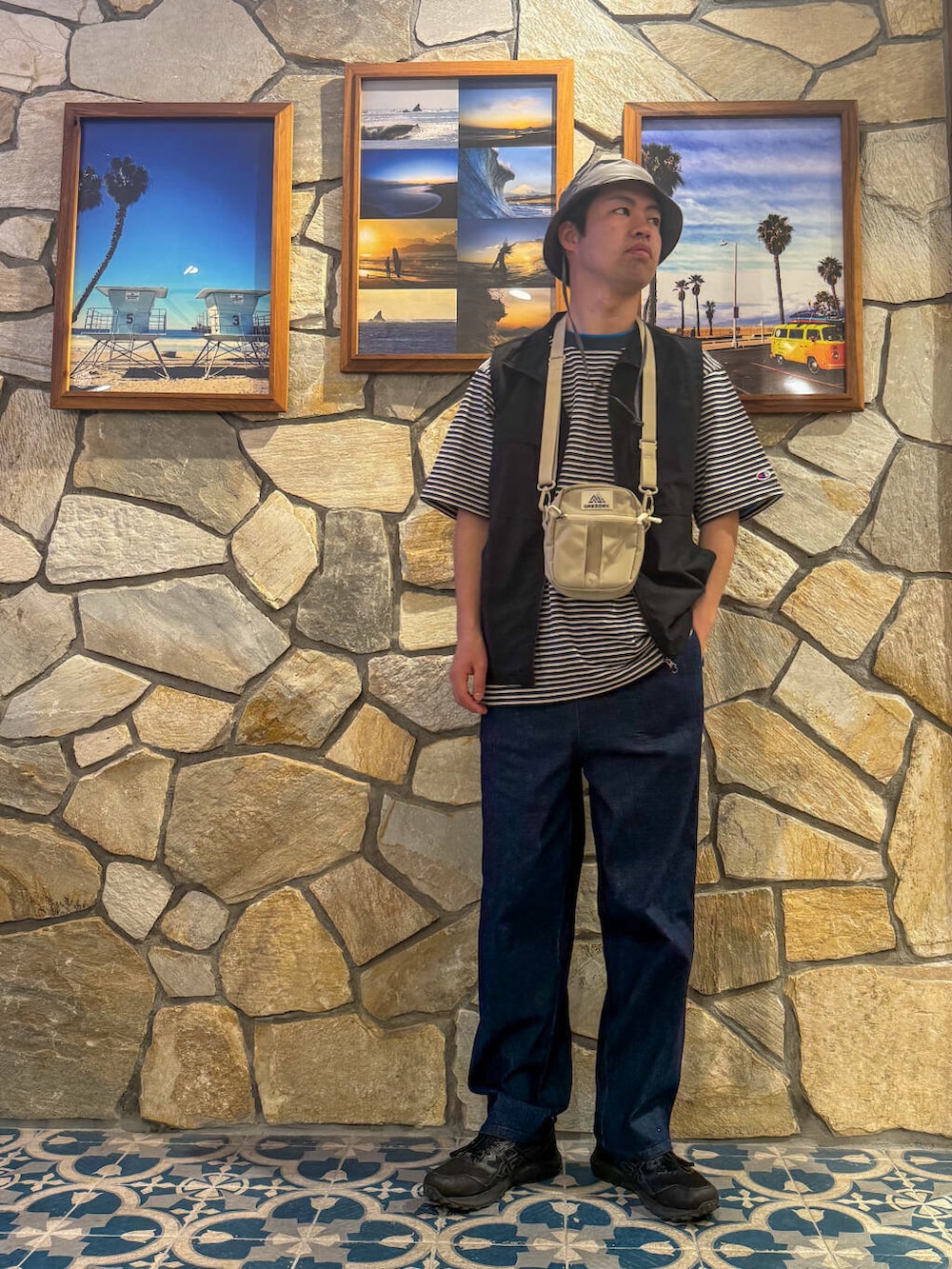 ブラック系のベスト、ベージュ系のショルダーバッグ、ブルー系のその他パンツを着用したメンズの春コーディネートの2枚目の写真