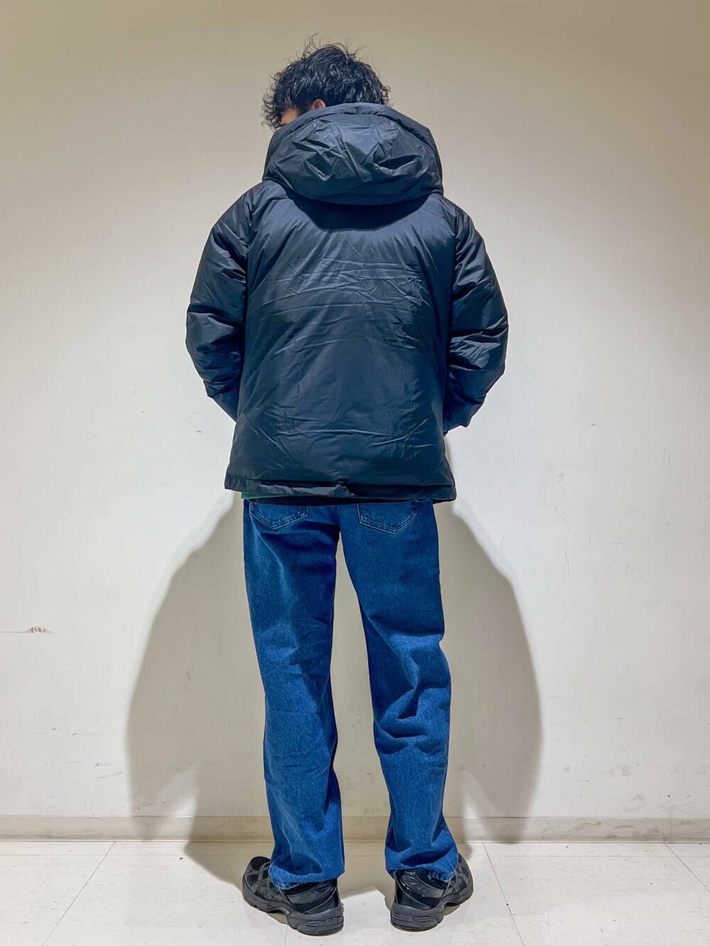 ブルー系のデニムパンツ、ブラック系のダウンジャケット/コート、グリーン系のスウェットを着用したメンズの秋コーディネートの4枚目の写真