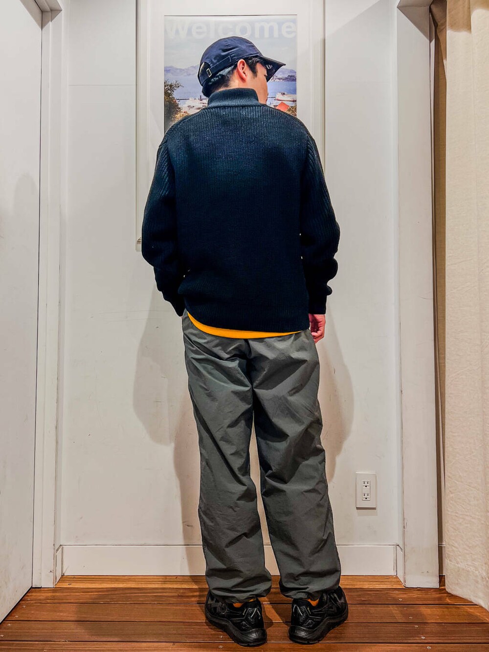 イエロー系のTシャツ/カットソー、ブラック系のニット/セーター、ブルー系のキャップを着用したメンズの冬コーディネートの2枚目の写真