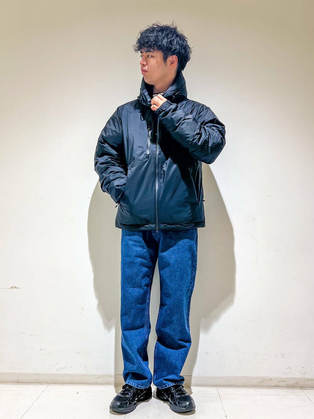 ブルー系のデニムパンツ、ブラック系のダウンジャケット/コート、グリーン系のスウェットを着用したメンズの秋コーディネートの2枚目の写真