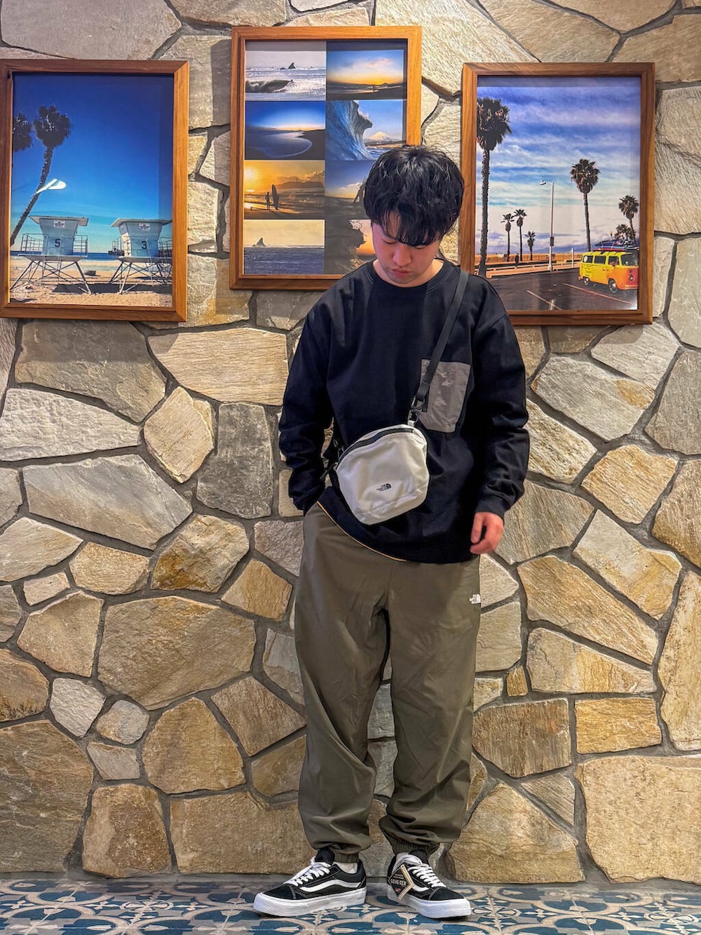 グリーン系のその他パンツ、グレー系のショルダーバッグ、ブラック系のTシャツ/カットソーを着用したメンズの春コーディネートの2枚目の写真