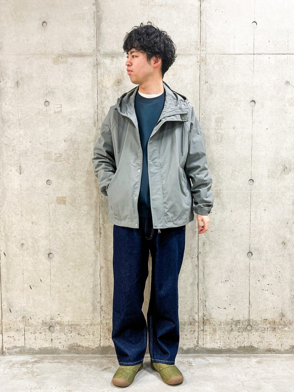 ブルー系のデニムパンツ、グレー系のマウンテンパーカー、グリーン系のスウェットを着用したメンズの冬コーディネートの2枚目の写真