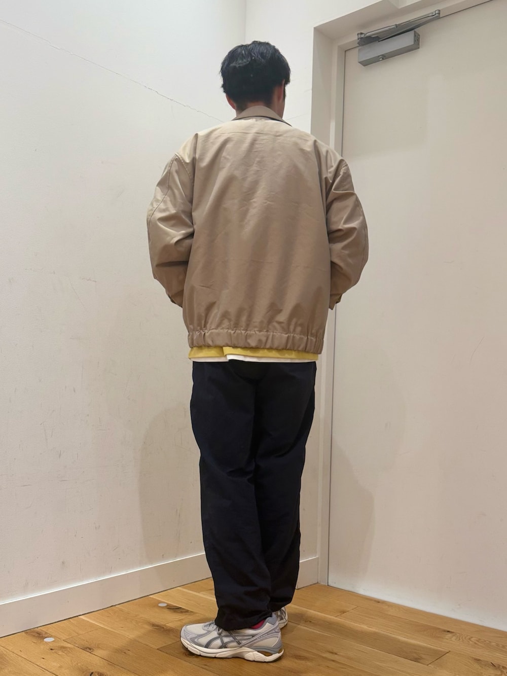 ベージュ系のブルゾン、イエロー系のTシャツ/カットソー、ホワイト系のスニーカーを着用したメンズの冬コーディネートの2枚目の写真