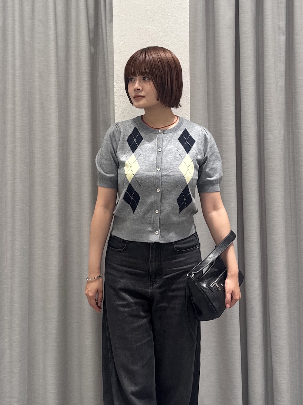 ブラック系のデニムパンツ、ブラック系のショルダーバッグ、グレー系のカーディガン/ボレロを着用したレディースの夏コーディネートの2枚目の写真