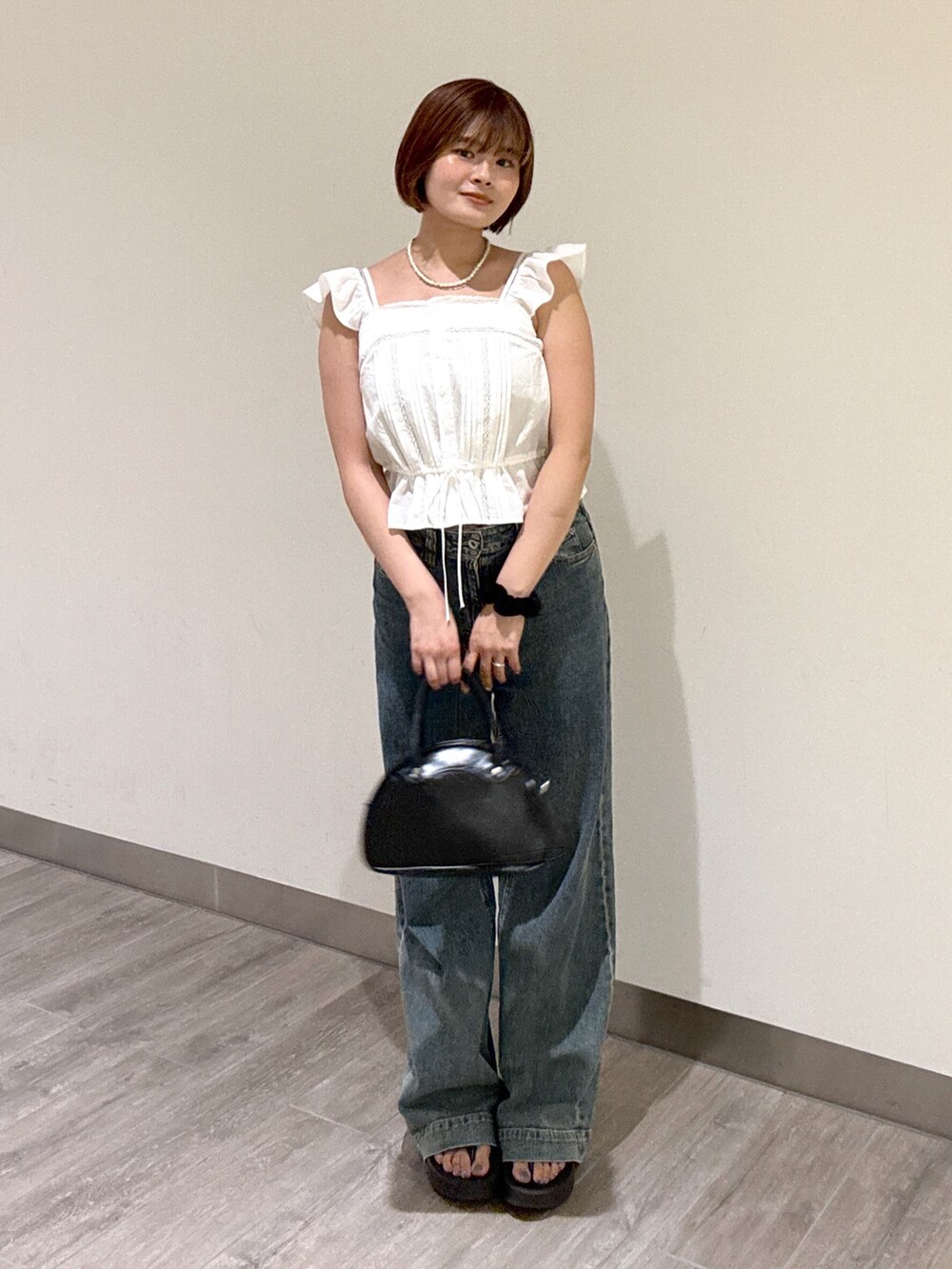 ブルー系のデニムパンツ、ブラック系のトートバッグ、ホワイト系のシャツ/ブラウスを着用したレディースの夏コーディネートの5枚目の写真