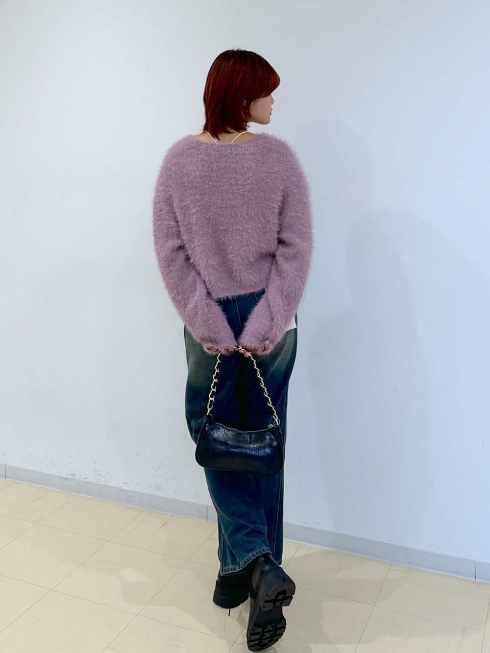 ブルー系のデニムパンツ、ブラック系のトートバッグ、ブラック系のブーツを着用したレディースの秋コーディネートの3枚目の写真