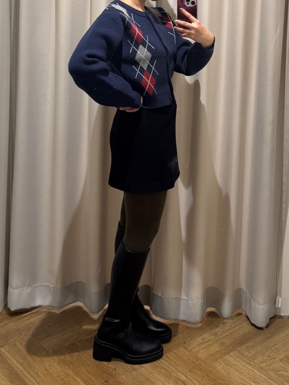 ブラック系のスカート、ブルー系のニット/セーター、ブラック系のブーツを着用したレディースの秋コーディネートの3枚目の写真