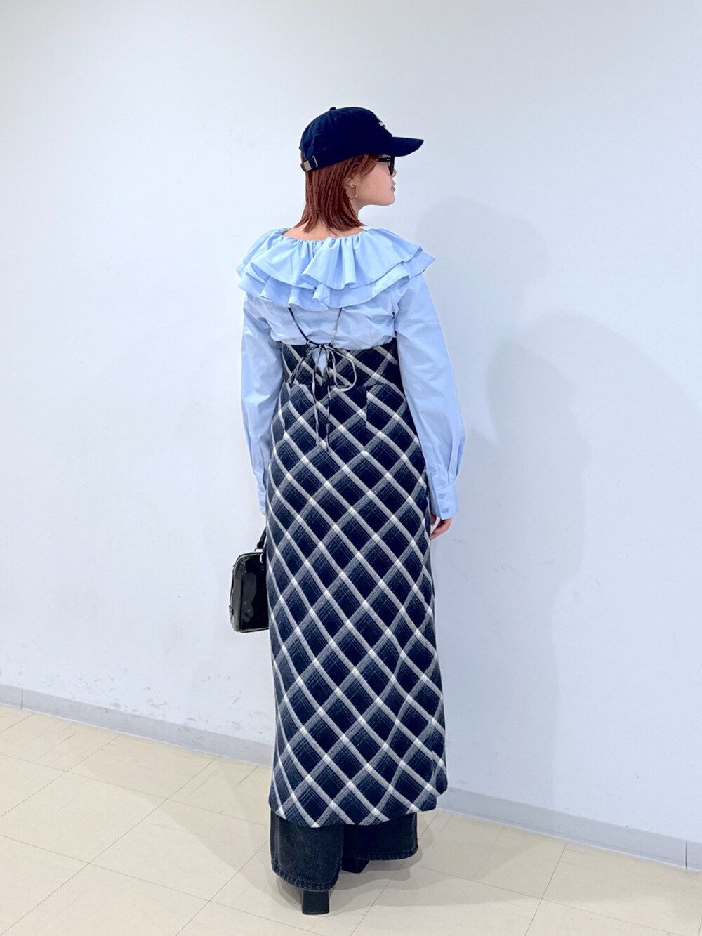 ブルー系のワンピース、ブラック系のショルダーバッグ、ブラック系のデニムパンツを着用したレディースの冬コーディネートの3枚目の写真