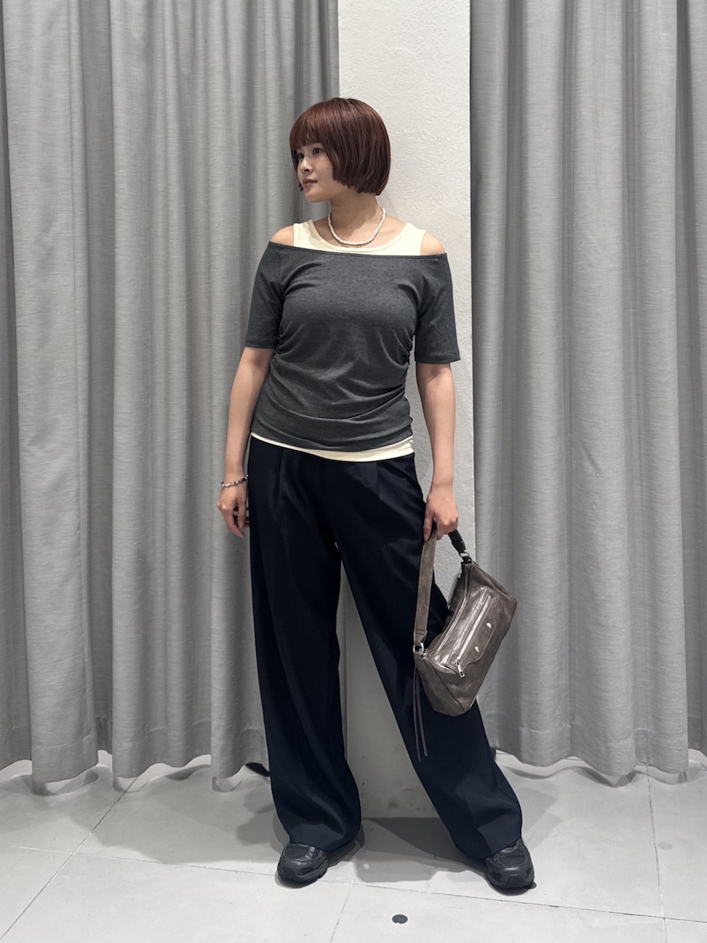 ブラウン系のショルダーバッグ、ブルー系のスラックス、グレー系のTシャツ/カットソーを着用したレディースの夏コーディネートの2枚目の写真