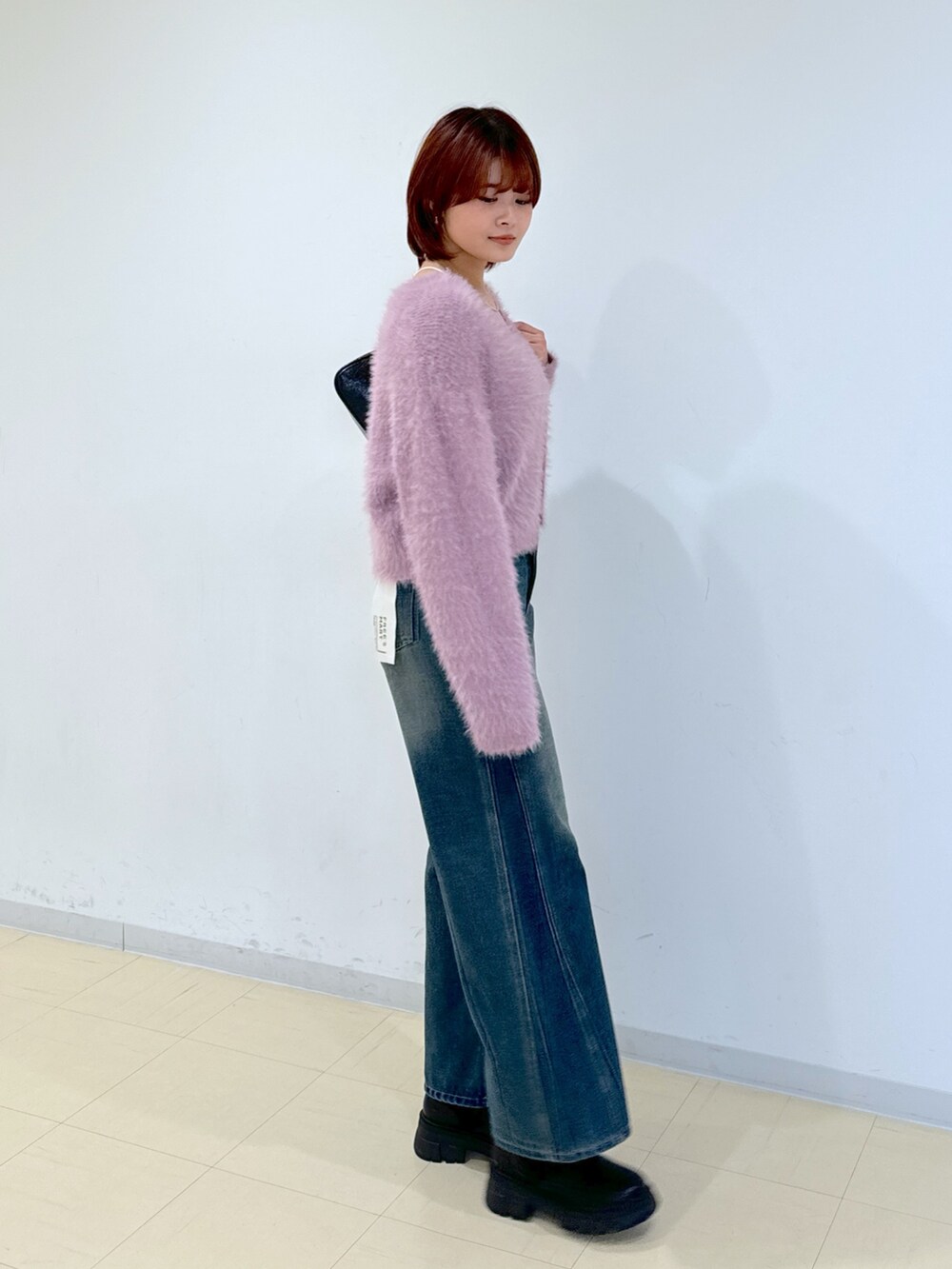 ブルー系のデニムパンツ、ブラック系のトートバッグ、ブラック系のブーツを着用したレディースの秋コーディネートの4枚目の写真