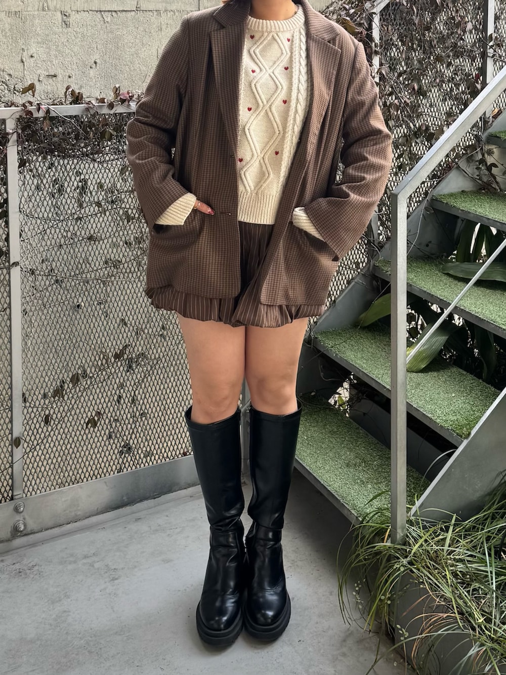 ホワイト系のニット/セーター、ブラウン系のスカート、ブラック系のブーツを着用したレディースの冬コーディネートの3枚目の写真