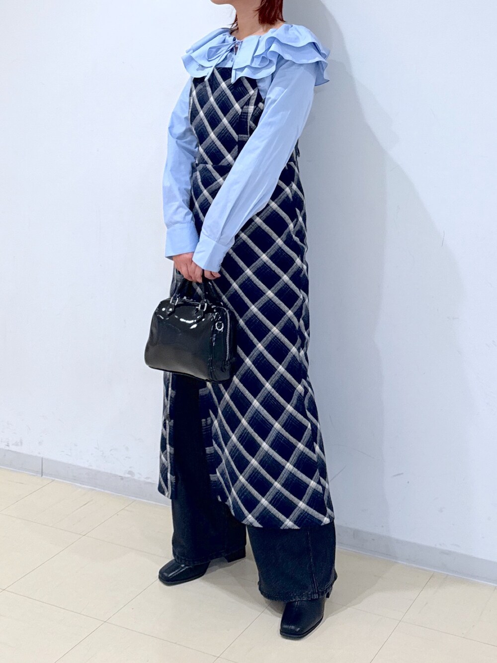 ブルー系のワンピース、ブラック系のショルダーバッグ、ブラック系のデニムパンツを着用したレディースの冬コーディネートの5枚目の写真