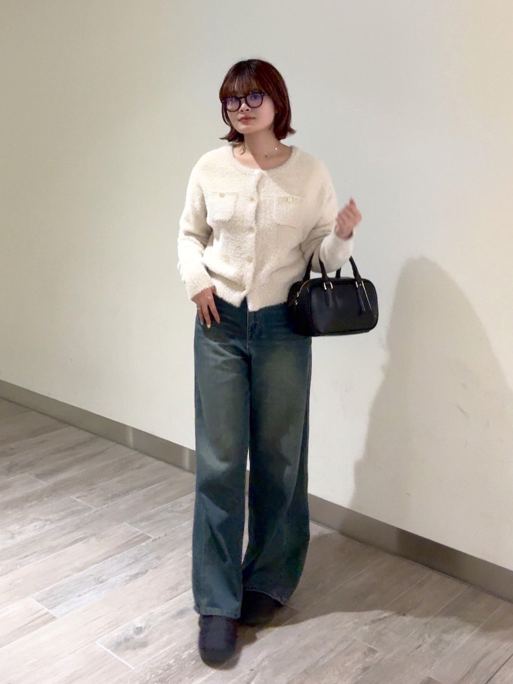 ブルー系のデニムパンツ、ブラック系のハンドバッグ、ベージュ系のニット/セーターを着用したレディースの冬コーディネートの5枚目の写真