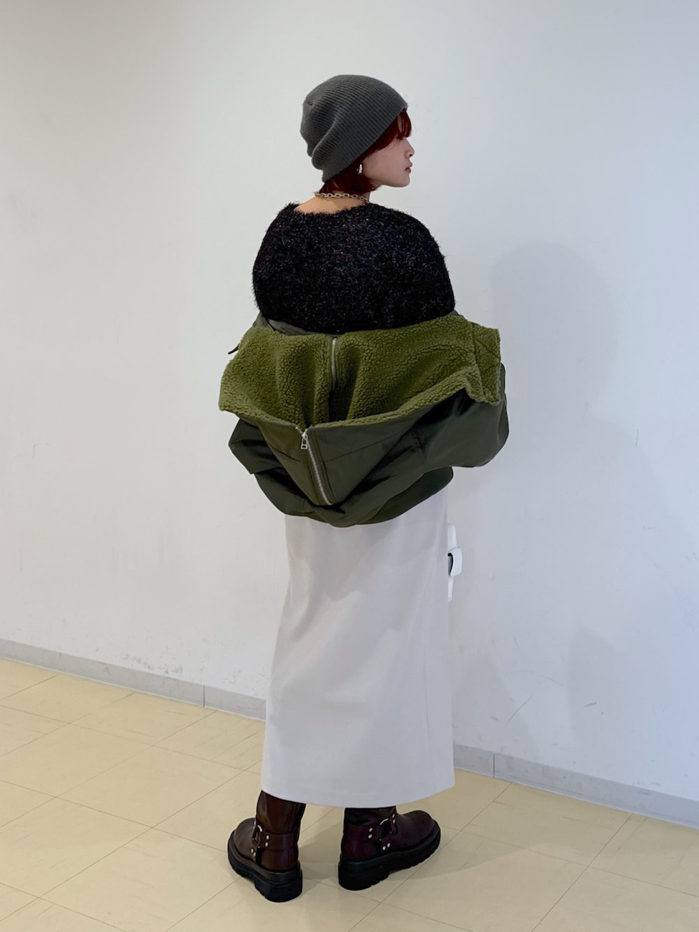 グリーン系のブルゾン、ホワイト系のハンドバッグ、ブラウン系のブーツを着用したレディースの冬コーディネートの3枚目の写真