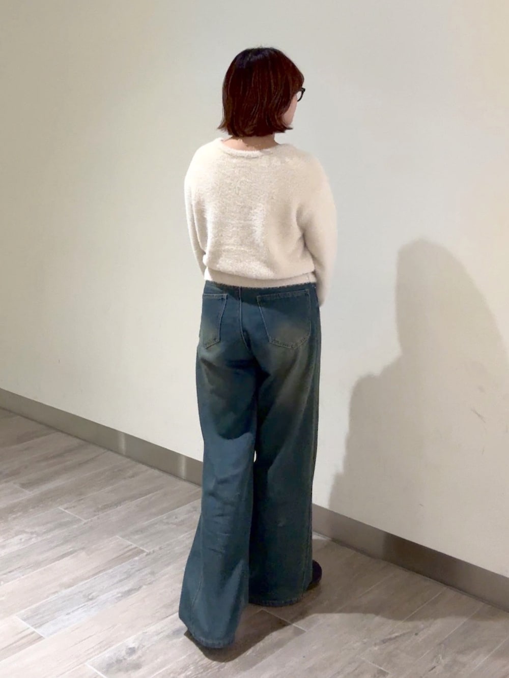 ブルー系のデニムパンツ、ブラック系のハンドバッグ、ベージュ系のニット/セーターを着用したレディースの冬コーディネートの3枚目の写真