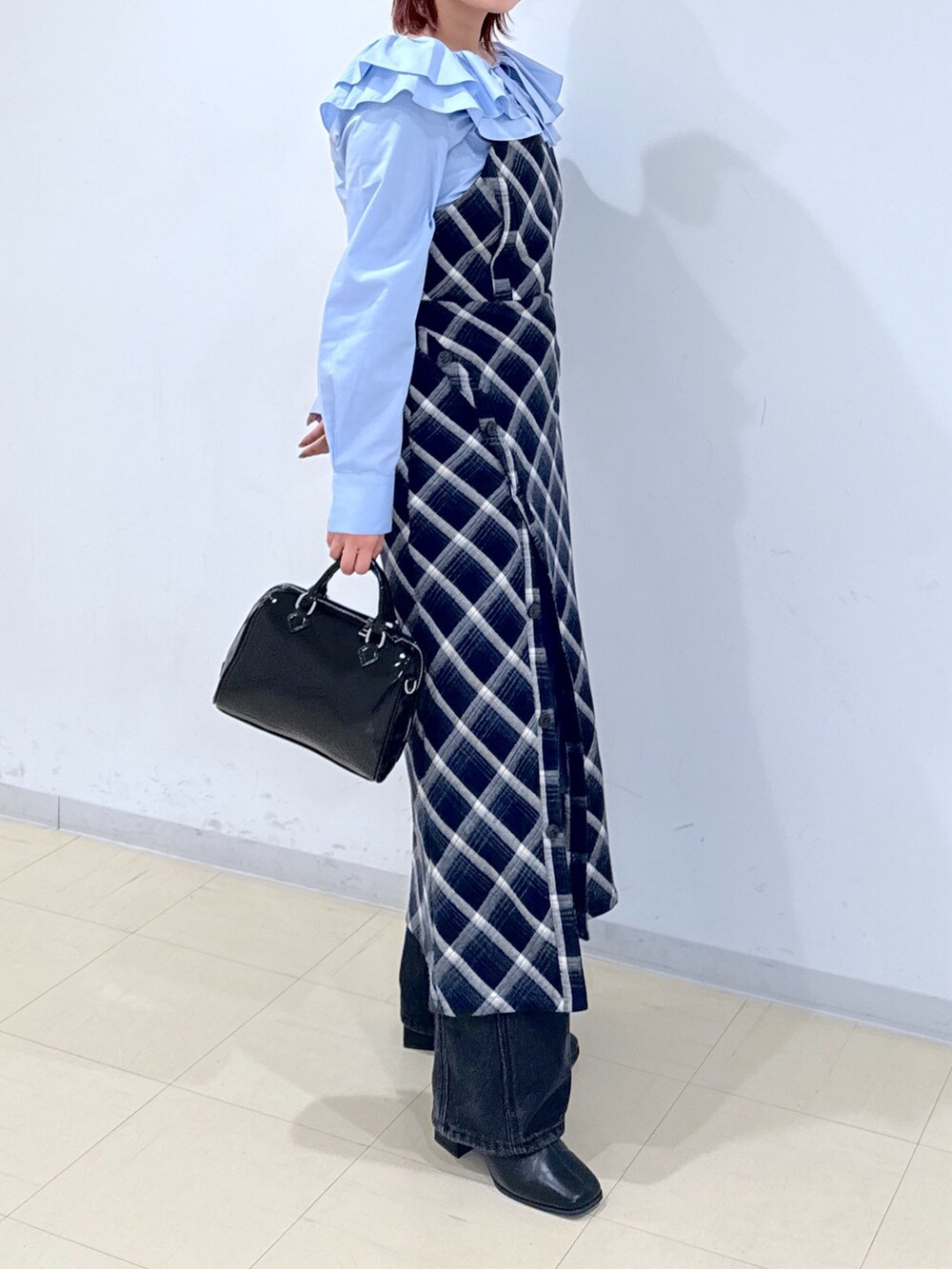 ブルー系のワンピース、ブラック系のショルダーバッグ、ブラック系のデニムパンツを着用したレディースの冬コーディネートの4枚目の写真