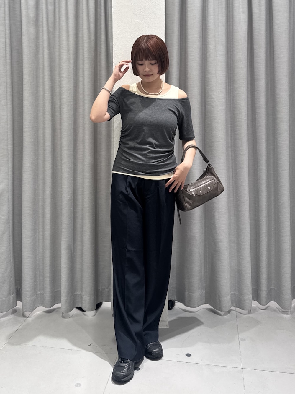 ブラウン系のショルダーバッグ、ブルー系のスラックス、グレー系のTシャツ/カットソーを着用したレディースの夏コーディネートの4枚目の写真