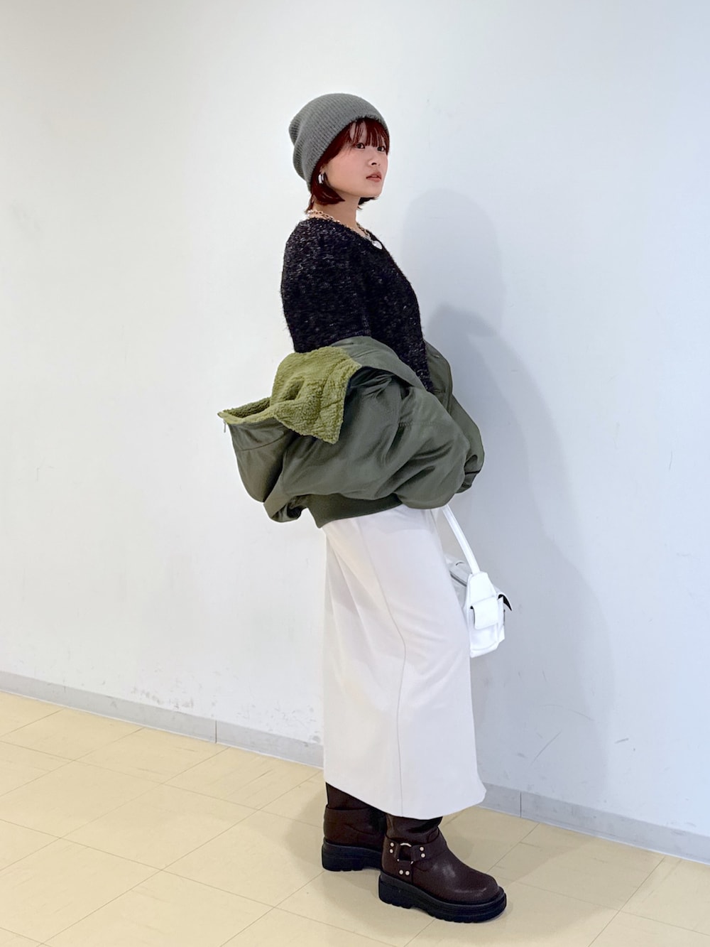 グリーン系のブルゾン、ホワイト系のハンドバッグ、ブラウン系のブーツを着用したレディースの冬コーディネートの2枚目の写真