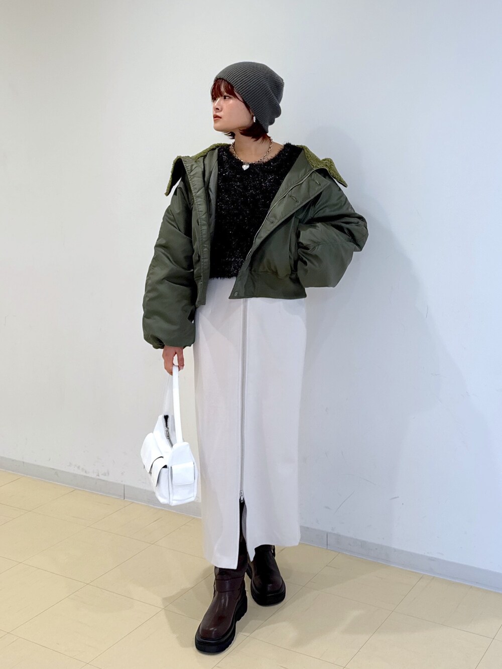 グリーン系のブルゾン、ホワイト系のハンドバッグ、ブラウン系のブーツを着用したレディースの冬コーディネートの4枚目の写真