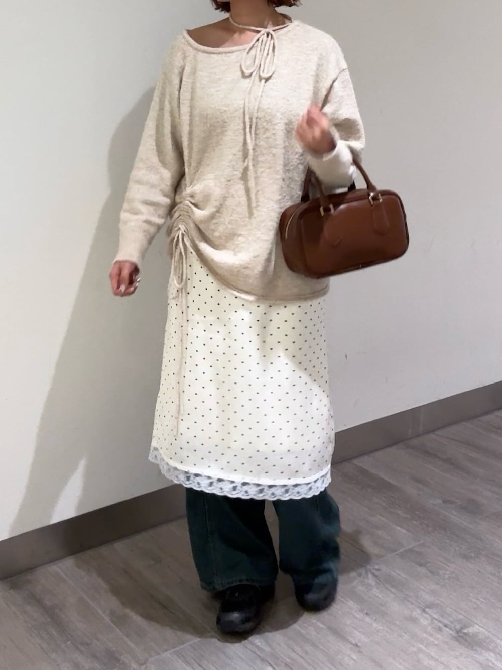 ベージュ系のニット/セーター、ホワイト系のスカート、ブルー系のデニムパンツを着用したレディースの冬コーディネートの2枚目の写真