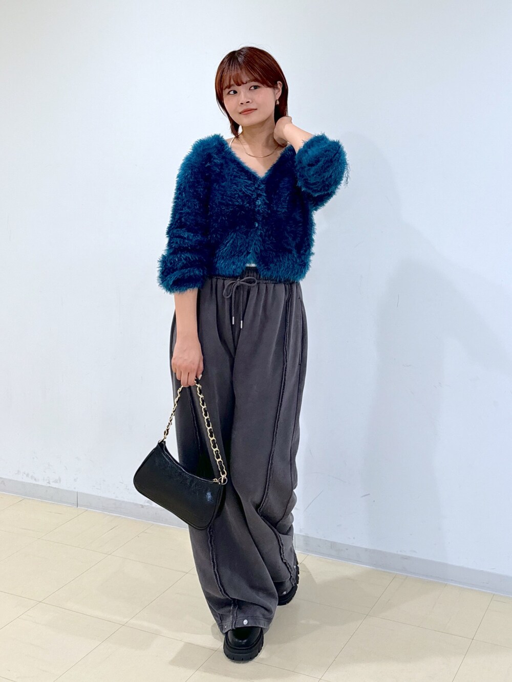 ブラック系のブーツ、グリーン系のカーディガン/ボレロ、ブラック系のトートバッグを着用したレディースの秋コーディネートの2枚目の写真