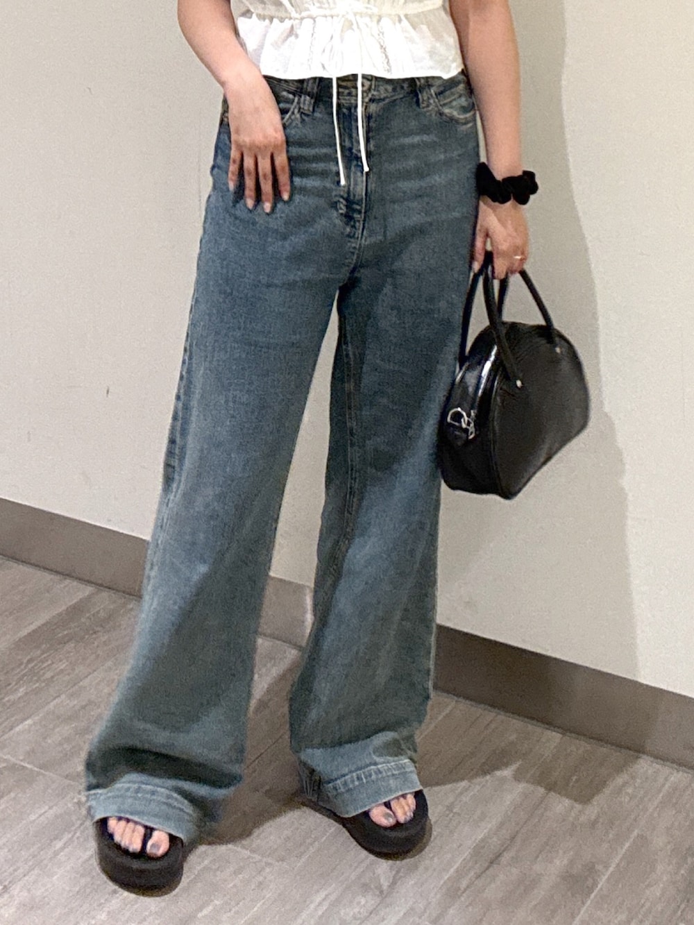 ブルー系のデニムパンツ、ブラック系のトートバッグ、ホワイト系のシャツ/ブラウスを着用したレディースの夏コーディネートの4枚目の写真