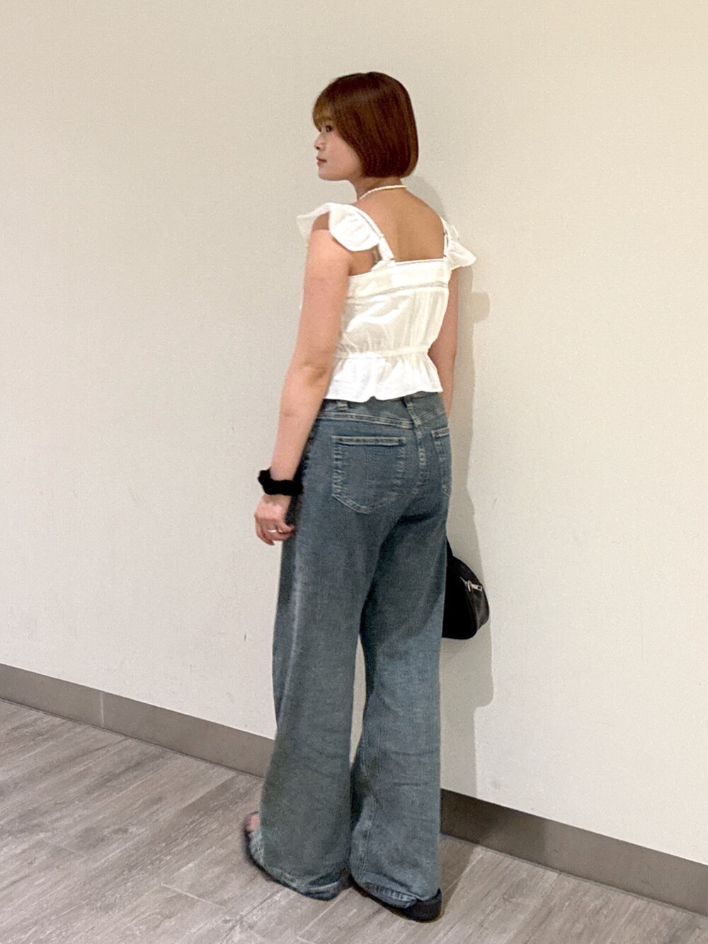 ブルー系のデニムパンツ、ブラック系のトートバッグ、ホワイト系のシャツ/ブラウスを着用したレディースの夏コーディネートの2枚目の写真